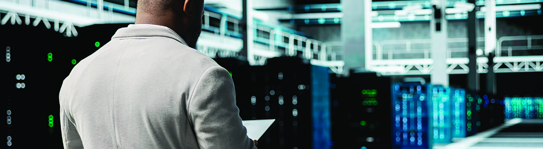 Man working in a data center surrounded by server racks Man working in a data center surrounded by server racks